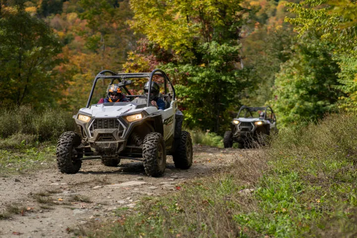 a man riding on the back of a truck driving down a dirt road